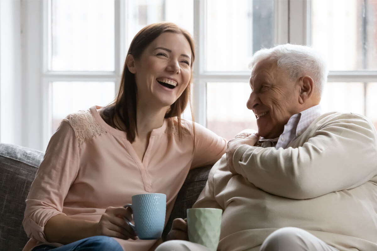 Adult daughter and senior father enjoy a cup of coffee together_Brickmont Assisted Living