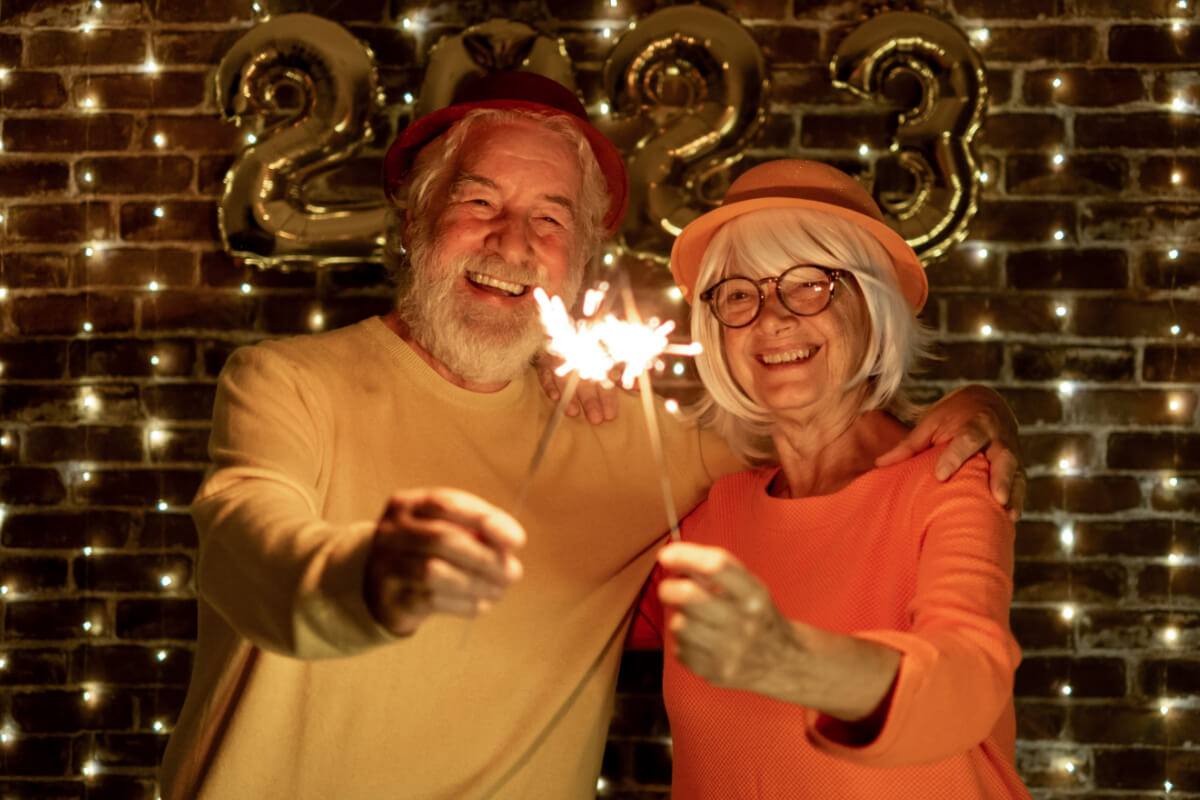 Older couple holding sparklers, in front of 